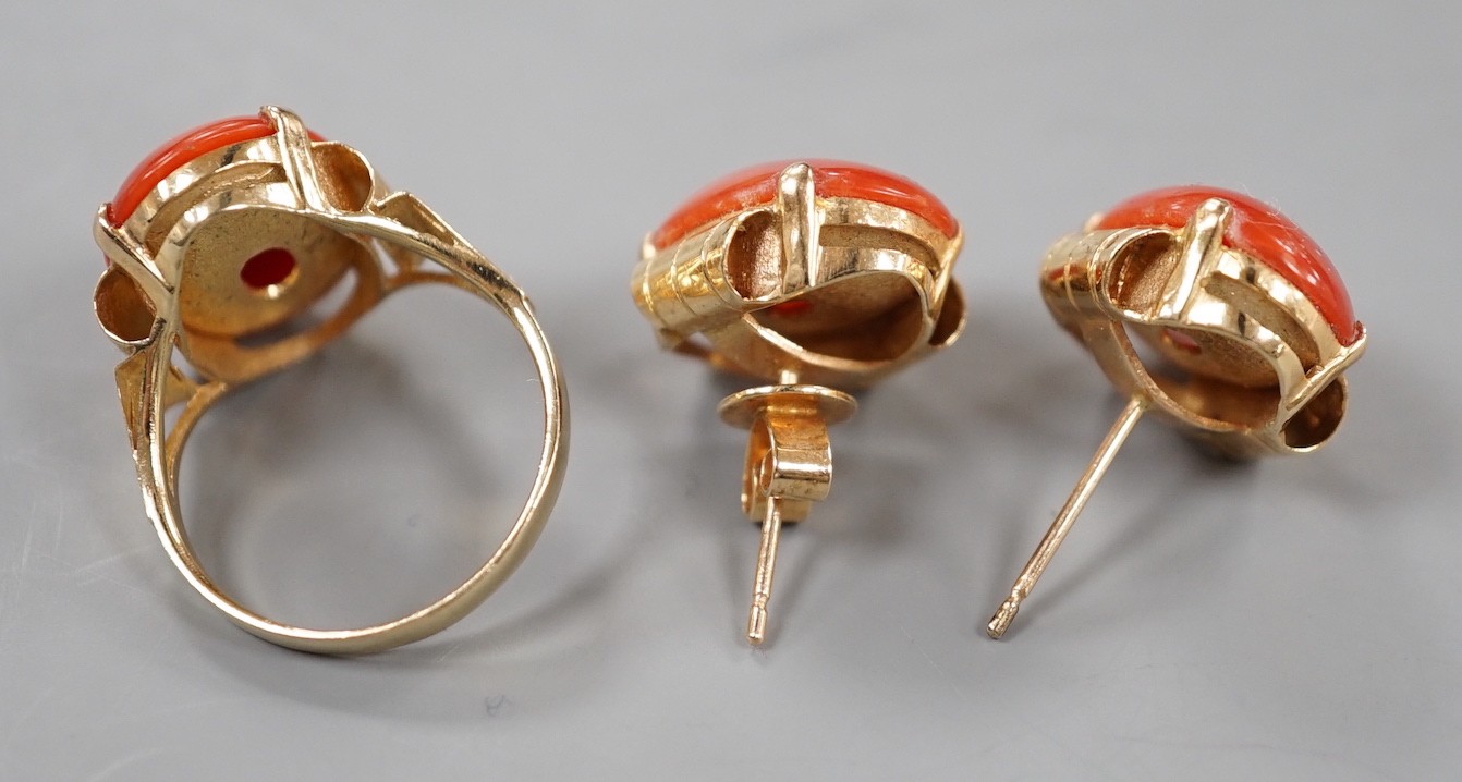 A 14k yellow metal and cabochon coral set oval ring, size N and a pair of matching earrings, lacking one butterfly, gross weight 11.5 grams.